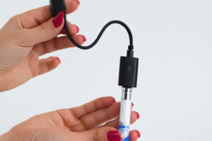 Woman's hands connect vape pen to USB 510 thread charger. 