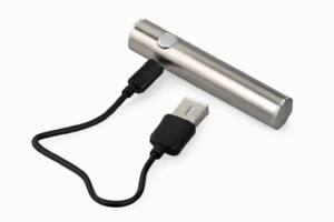 A stainless steel vape pen battery with a black charging cable. 
